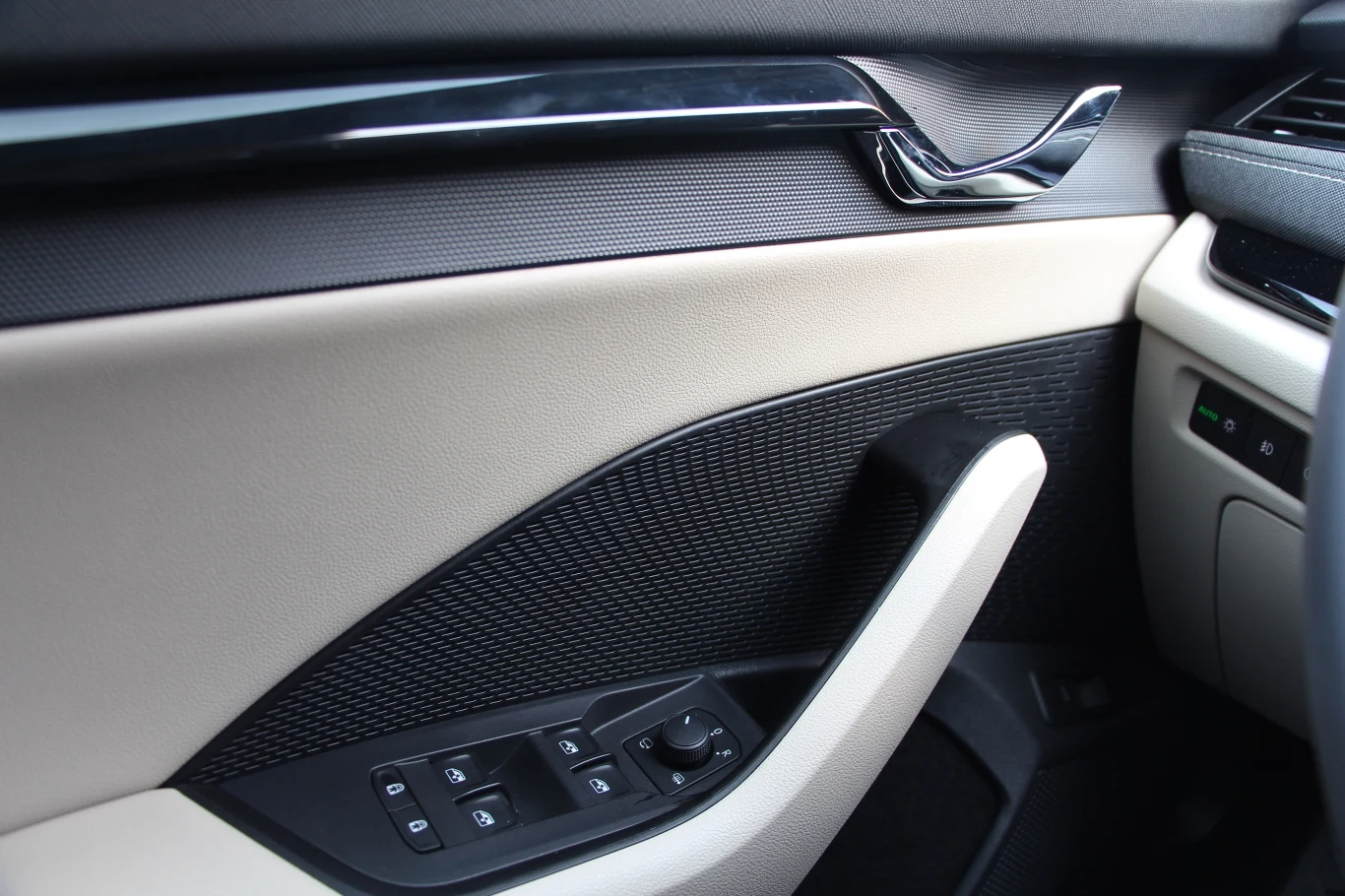 Listwa ozdobna płynnie przechodzi w ciekawie zaprojektowaną klamkę. Samo wykończenie drzwi urozmaicono wykorzystując różne rodzaje materiałów. Duża ciemna powierzchnia ma miejscami ciekawą fakturę i na pierwszy rzut oka nie wygląda na kawałek plastiku, którym jest. Ukryto w nim głośnik.