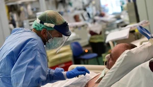 Lekarz pochyla się nad pacjentem zakażonym koronawirusem, zdjęcie ilustracyjne