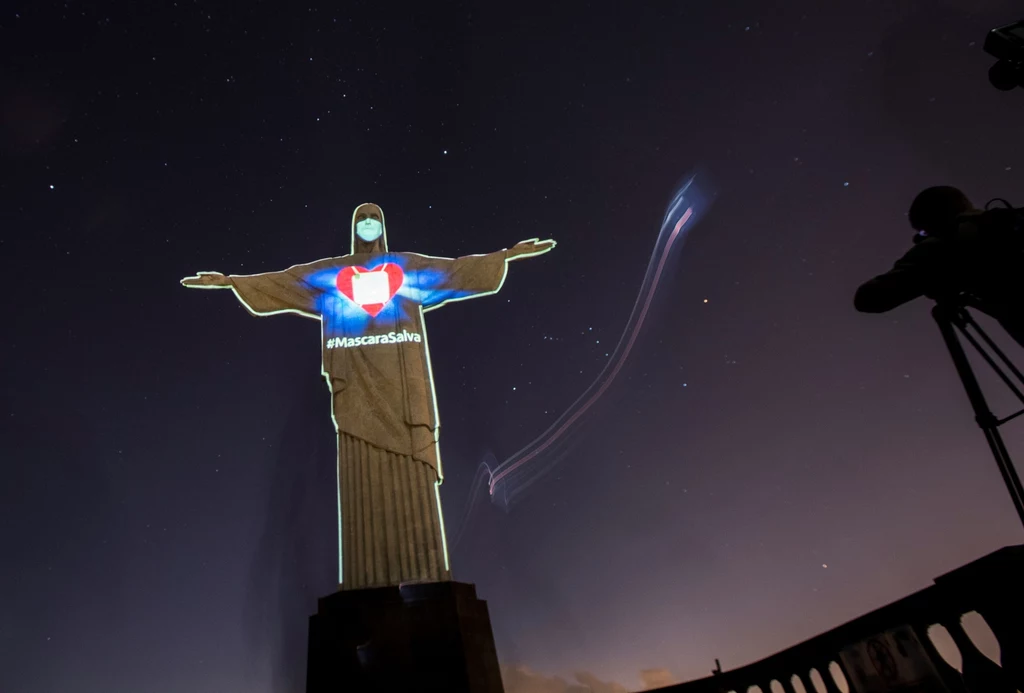 Dzięki grze świateł mieszkańcy Rio de Janeiro mogą odnieść wrażenie, że na twarzy Jezusa pojawiła się maseczka ochronna. Dzięki grze świateł mieszkańcy Rio de Janeiro mogą odnieść wrażenie, że na twarzy Jezusa pojawiła się maseczka ochronna.