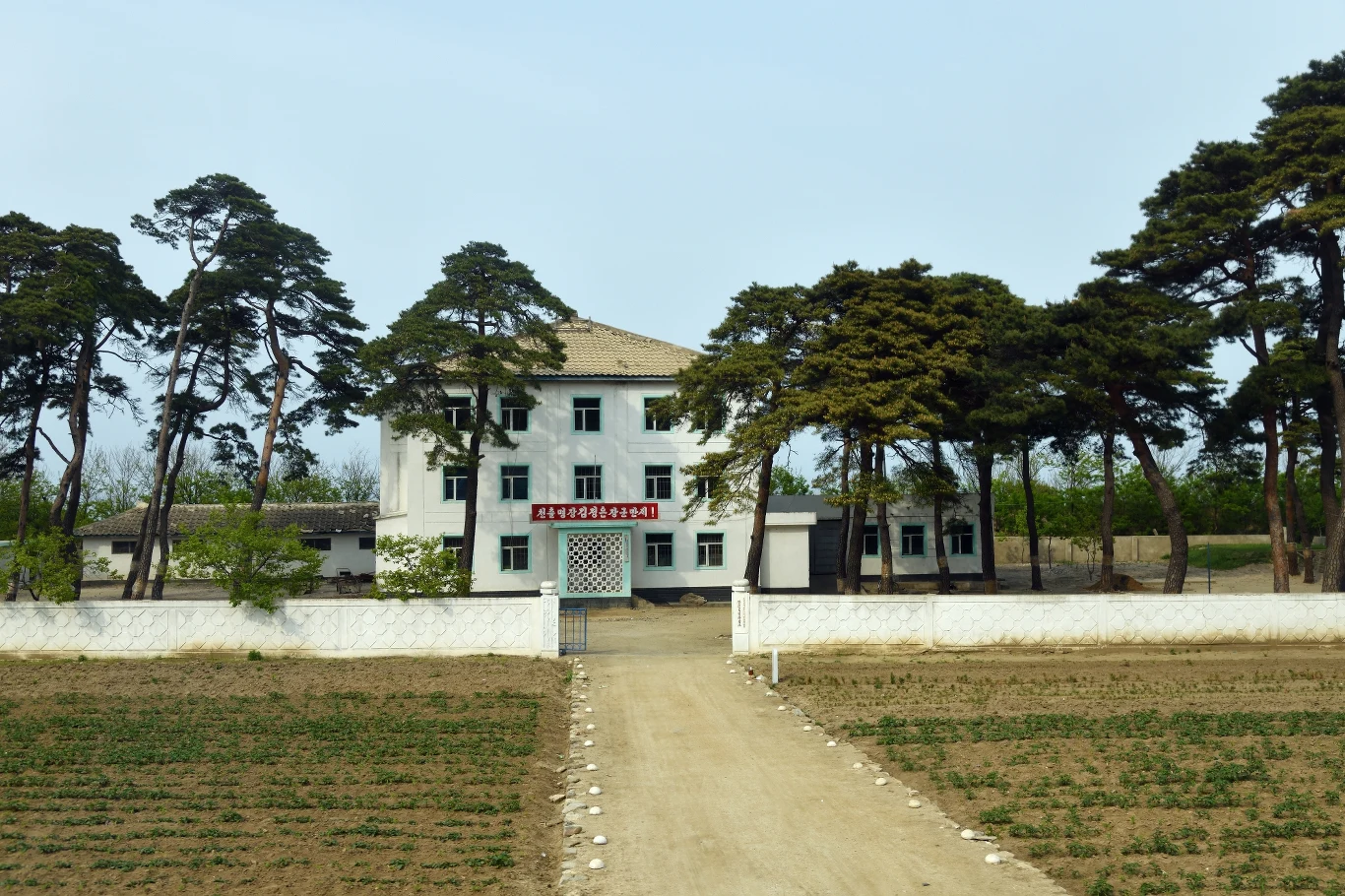 Rezydencje w Pjongjang i Wonsan - Korea Północna Korea Połnocna należy do najbardziej wyizolowanych krajów na świecie. Choć na jej teren organizowane są wycieczki, ich trasy z pewnością nie obejmują zwiedzania rezydencji "Najwyższego Przywódcy Partii, Armii i Narodu" . Te są pilnie strzeżone (prawdopodobnie najpilniej na świecie), a wstęp do nich mają wyłącznie przedstawiciele władz i służb bezpieczeństwa. Z rzadka zapraszani są tam również przedstawiciele zagranicznych państw, milionerzy i zaprzyjaźnieni z Kim Dzong Unem celebryci. Jednak, jako że informacyjne granice są o wiele mniej szczelne niż te geograficzne, od czasu do czasu na zachód przeciekają rewelacje dotyczące warunków, w jakich żyje i pracuje północnokoreański przywódca. Bez wątpienia są to standardy nieporównywalnie wyższe od tych, w jakich żyje większość Koreańczyków z północy. Główną siedzibą przywódcy jest rezydencja w Pjongjangu, której część kilka lat temu odwiedził Siergiej Ławrow. Przy okazji tej wizyty, wykonano zdjęcia, które opublikowane zostały w zachodnich mediach. Jak nietrudno się domyślić widzimy na nich pełne przepychu wnętrza: marmurowe kolumny, stiuki, złocone klamki, puszyste dywany i lśniący parkiet. Pałac Pjongjangu to tylko jedna z kilku (mówi się o ośmiu) rezydencji północnokoreańskiego władcy. Jego ukochanym miejscem jest ponoć nadmorski kurort w Wonsan. Na należącej do Kim Dzong Una posesji mieszczą się rezydencje członków jego rodziny oraz kilka domów gościnnych. Do dyspozycji mieszkańców jest ogród, kryty basen, jachty, łódki, lądowisko dla helikopterów i boisko do koszykówki. Co ciekawe, na tym terenie znajduje się również wyrzutnia rakiet. Na zdjęciu prezentujemy jedne z należących do władz budynków znajdujących się w kompleksie wypoczynkowym w Wonsan.