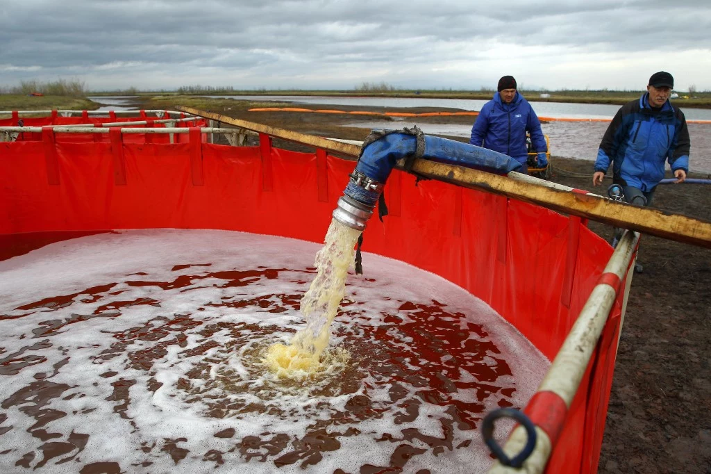 Pracownicy firmy petrochemicznej wypompowują zanieczyszczającą rzekę olej