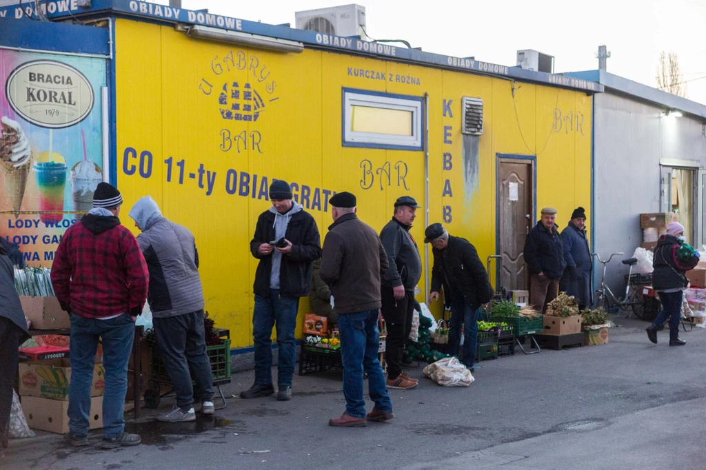 Targowiska Choć w ferworze codziennych zakupów mało kto zwraca uwagę na estetykę otoczenia, wystarczy na chwilę oderwać wzrok od straganu z warzywami, żeby zauważyć, że większość polskich targowisk to budowlany i reklamowy mix, którego nie powstydziłyby się brazylijskie fawele. Na polskich targowiskach drewniane stoiska sąsiadują z budkami z blachy falistej, blacha z konstrukcjami z pustaków, a pustaki z oszklonymi wiatami. Między tą „małą architekturą” są i stanowiska efemeryczne, z towarami rozłożonymi na kartonach oraz handel prowadzony wprost z bagażnika. Całości obrazka dopełniają bary, piekarnie i toalety. Czy tę przestrzeń da się jakoś uładzić? Patrząc na pejzaż polskich miast, chciałoby się powiedzieć: tak, ale potrzeba na to czasu. Za przykład może posłużyć krakowskie targowisko „Tandeta”: w miejscu straganów na początku lat 2000. stanęła tam nowoczesna hala i choć jej bryła pozostawia wiele do życzenia, przestrzenny chaos udało się opanować. Targowiska Choć w ferworze codziennych zakupów mało kto zwraca uwagę na estetykę otoczenia, wystarczy na chwilę oderwać wzrok od straganu z warzywami, żeby zauważyć, że większość polskich targowisk to budowlany i reklamowy mix, którego nie powstydziłyby się brazylijskie fawele. Na polskich targowiskach drewniane stoiska sąsiadują z budkami z blachy falistej, blacha z konstrukcjami z pustaków, a pustaki z oszklonymi wiatami. Między tą „małą architekturą” są i stanowiska efemeryczne, z towarami rozłożonymi na kartonach oraz handel prowadzony wprost z bagażnika. Całości obrazka dopełniają bary, piekarnie i toalety. Czy tę przestrzeń da się jakoś uładzić? Patrząc na pejzaż polskich miast, chciałoby się powiedzieć: tak, ale potrzeba na to czasu. Za przykład może posłużyć krakowskie targowisko „Tandeta”: w miejscu straganów na początku lat 2000. stanęła tam nowoczesna hala i choć jej bryła pozostawia wiele do życzenia, przestrzenny chaos udało się opanować.
