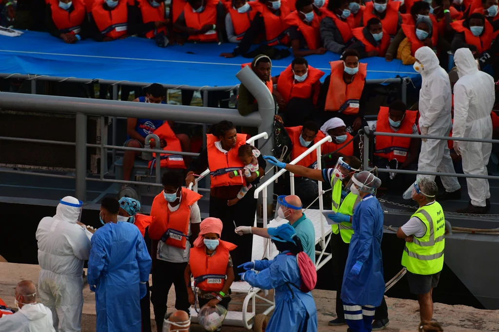Tymczasem w ostatnich dniach setki migrantów dotarły na niewielkich łodziach z Afryki Północnej na włoskie wybrzeża. Kryzysowa sytuacja panuje na wyspie Lampedusa. W nocy z niedzieli na poniedziałek grupa mieszkańców wyspy zablokowała drogę domagając się natychmiastowej ewakuacji przybyszów. Na zdjęciu: Migranci uratowani 27 lipca 2020 przez maltańskie służby Tymczasem w ostatnich dniach setki migrantów dotarły na niewielkich łodziach z Afryki Północnej na włoskie wybrzeża. Kryzysowa sytuacja panuje na wyspie Lampedusa. W nocy z niedzieli na poniedziałek grupa mieszkańców wyspy zablokowała drogę domagając się natychmiastowej ewakuacji przybyszów. Na zdjęciu: Migranci uratowani 27 lipca 2020 przez maltańskie służby
