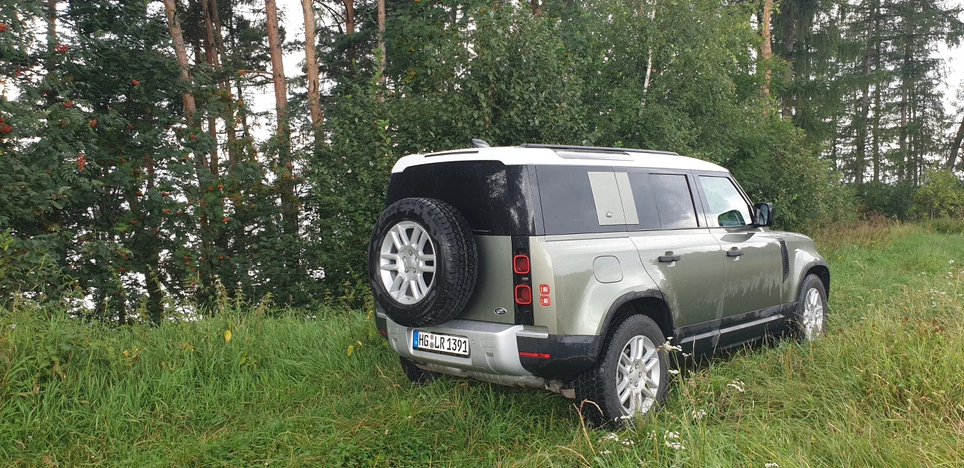 Land Rover zdecydował się pozbawić Defendera osobnej dźwigni do sterowanie napędem. Zamiast tego mamy do dyspozycji predefiniowane ustawienia na różne rodzaje nawierzchni lub możliwość wybrania funkcji Auto i zdania się na to, że elektronika sama wykryje z jakim terenem ma do czynienia. Samochód wyposażony jest w reduktor i stały napęd na cztery koła z blokadą centralnego mechanizmu różnicowego. Na liście opcji znajdziemy blokadę także tylnego "dyfra" oraz... pneumatyczne zawieszenie z regulacją prześwitu. 