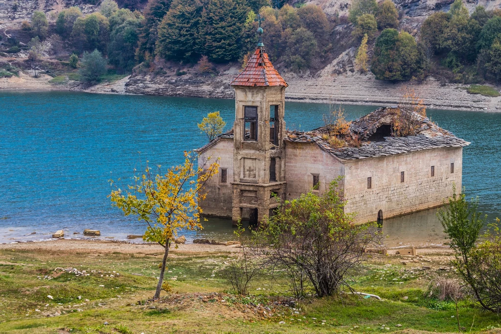 Kościół św. Mikołaja w miejscowości Mawrowo w Macedonii został zbudowany w 1850 roku i był dumą miejscowej społeczności. Marmurowy ołtarz, bogato zdobiony ikonostas, piękne ikony, książki i inne przedmioty użytku religijnego – ten wiejski kościółek był prawdziwą perełką. Krach nadszedł wraz z budową elektrowni wodnej Mawrowo. Teren został zalany, a kościółek zniknął pod wodą. Część cennych przedmiotów uratowano, o niektórych zapomniano. Choć był czas, gdy jedynie szczyt wieży ponad wodą przypominał o kościele, liczne susze znacznie obniżyły poziom wody i budowla zaczęła „powracać do żywych”. Szczególnie w miesiącach letnich zdarzało się, że kościół „wychodził na ląd” i można było do niego dojść suchą stopą. Kilka lat temu znalazła się również firma, która postanowiła odremontować budynek i przywrócić mu dawną świetność. Widać tej świątyni nie było pisane być „podwodnym kościołem”. Kościół św. Mikołaja w miejscowości Mawrowo w Macedonii został zbudowany w 1850 roku i był dumą miejscowej społeczności. Marmurowy ołtarz, bogato zdobiony ikonostas, piękne ikony, książki i inne przedmioty użytku religijnego – ten wiejski kościółek był prawdziwą perełką. Krach nadszedł wraz z budową elektrowni wodnej Mawrowo. Teren został zalany, a kościółek zniknął pod wodą. Część cennych przedmiotów uratowano, o niektórych zapomniano. Choć był czas, gdy jedynie szczyt wieży ponad wodą przypominał o kościele, liczne susze znacznie obniżyły poziom wody i budowla zaczęła „powracać do żywych”. Szczególnie w miesiącach letnich zdarzało się, że kościół „wychodził na ląd” i można było do niego dojść suchą stopą. Kilka lat temu znalazła się również firma, która postanowiła odremontować budynek i przywrócić mu dawną świetność. Widać tej świątyni nie było pisane być „podwodnym kościołem”.