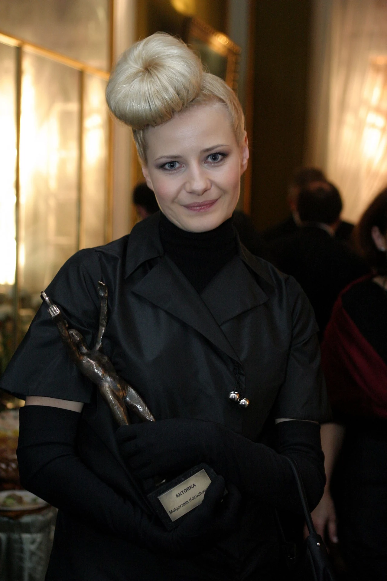 Małgorzata Kożuchowska Małgorzata Kożuchowska to bez wątpienia jedna z najpopularniejszych i najbardziej lubianych polskich aktorek. Na wielkim ekranie zadebiutowała w filmie "Kiler", ale popularność przyniosła jej rola Hanki w serialu "M jak miłość". Aktorka regularnie występuje również na deskach teatru, zajmuje się dubbingiem, śpiewa i jest ambasadorką kilku marek kosmetycznych. Małgorzata nie kryje również swojej miłości do mody, z którą śmiało eksperymentuje. W 2004 roku, podczas gali wręczenia statuetek "Telekamery", aktorka zaskoczyła fanów. Do czarnej kreacji dobrała długie rękawiczki i podkolanówki w tym samym kolorze, ale największe zainteresowanie wzbudziła fryzura gwiazdy. Kok miał imitować toczek, jednak zdaniem niektórych bardziej przypominał bocianie gniazdo i nie dodał aktorce urody. 