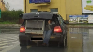 Z bagażnika wystawała lodówka, a obok niej siedział mężczyzna, którego nogi zwisały ku jezdni