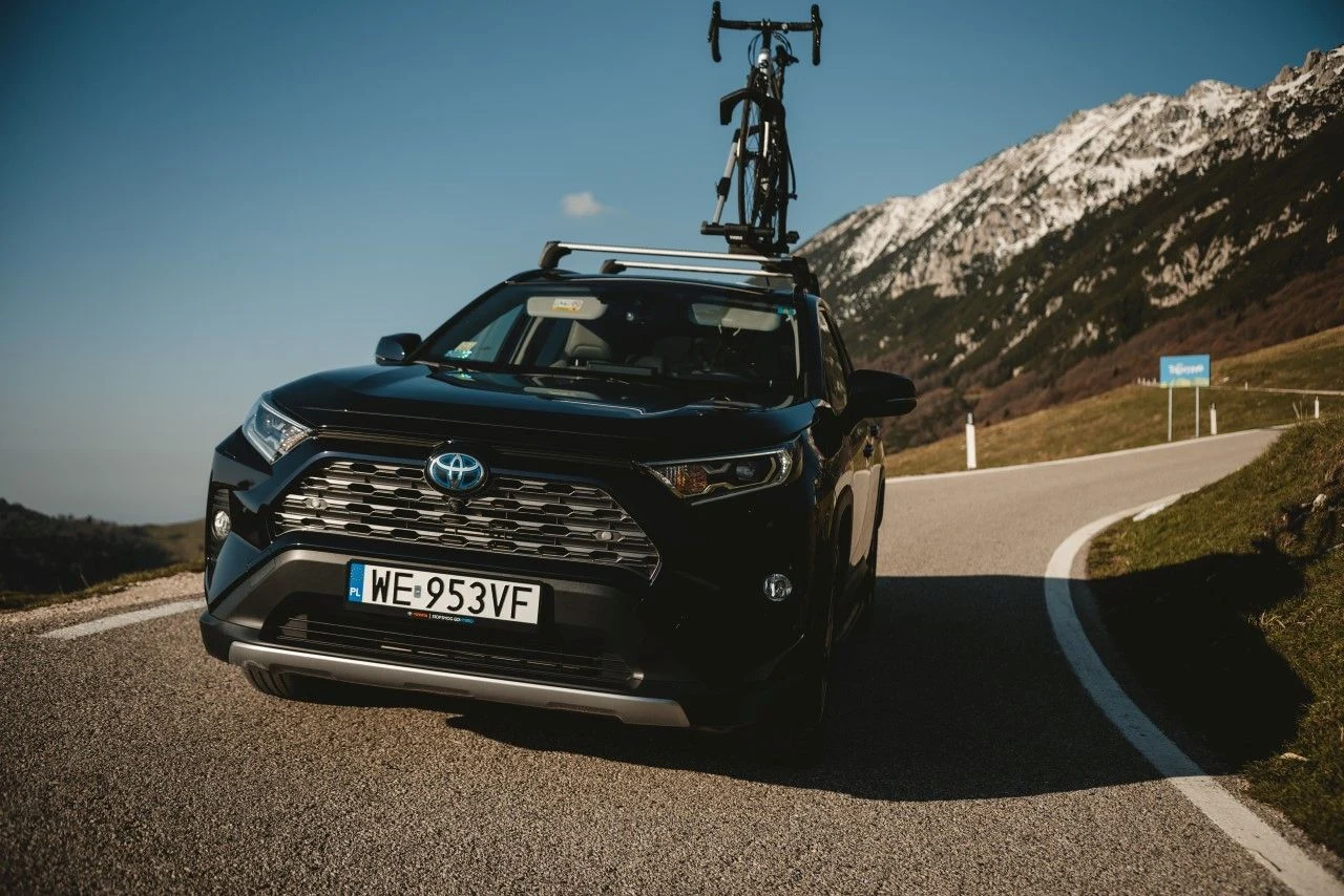 Hybrydowe RAV4 może się pochwalić nie tylko solidną konstrukcją SUV-a, dużymi gabarytami i mocnym napędem hybrydowym 2,5 l, ale także elektrycznym napędem na cztery koła AWD-i – to wszystko składa się na duże możliwości RAV4 jeśli chodzi o ciągnięcie drugiego pojazdu. Przyczepa z hamulcami o masie do 800 kg może jechać za hybrydowym RAV4 z napędem na przód o mocy 218 KM. Napęd na wszystkie koła, który opiera się na dodatkowym silniku elektrycznym przy tylnej osi i zwiększa moc auta do 222 KM, pozwala pociągnąć przyczepę ważącą aż 1650 kg. Auto jest standardowo wyposażone w system stabilizacji toru przyczepy. RAV4 mieści w bagażniku 580 l (do wysokości rolety), bez względu na rodzaj napędu. Przestrzeń tę można powiększyć do 1690 l, składając tylną kanapę. W tym modelu również może się znaleźć bezdotykowo otwierana tylna klapa, która jednak jest standardowo dezaktywowana przy montażu haka holowniczego. Podłoga bagażnika może być podwójna i dwustronna – tak jak w Corolli TS Kombi. Hybrydowe RAV4 może się pochwalić nie tylko solidną konstrukcją SUV-a, dużymi gabarytami i mocnym napędem hybrydowym 2,5 l, ale także elektrycznym napędem na cztery koła AWD-i – to wszystko składa się na duże możliwości RAV4 jeśli chodzi o ciągnięcie drugiego pojazdu. Przyczepa z hamulcami o masie do 800 kg może jechać za hybrydowym RAV4 z napędem na przód o mocy 218 KM. Napęd na wszystkie koła, który opiera się na dodatkowym silniku elektrycznym przy tylnej osi i zwiększa moc auta do 222 KM, pozwala pociągnąć przyczepę ważącą aż 1650 kg. Auto jest standardowo wyposażone w system stabilizacji toru przyczepy. RAV4 mieści w bagażniku 580 l (do wysokości rolety), bez względu na rodzaj napędu. Przestrzeń tę można powiększyć do 1690 l, składając tylną kanapę. W tym modelu również może się znaleźć bezdotykowo otwierana tylna klapa, która jednak jest standardowo dezaktywowana przy montażu haka holowniczego. Podłoga bagażnika może być podwójna i dwustronna – tak jak w Corolli TS Kombi.