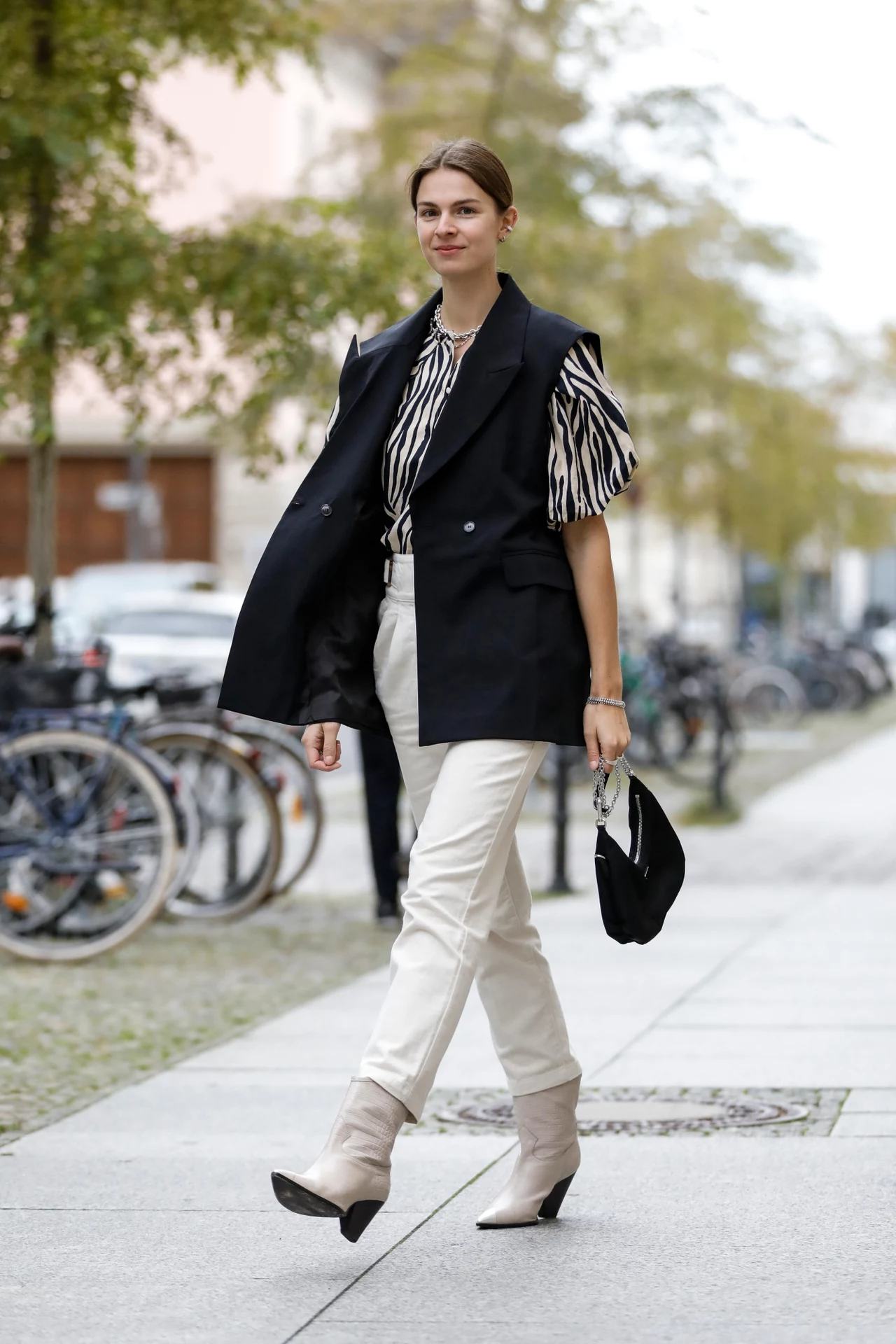Jacqueline Zelwis ma na sobie kamizelkę od Brigitte Herskind, bluzkę w motyw zebry od Sezane, kremowe spodnie od Sezane, torebkę Prada i buty Lola Cruz.