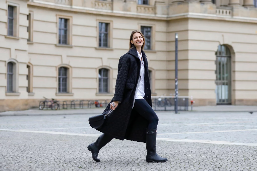 Jacqueline Zelwis ma na sobie czarny płaszcz od Birgitte Herskind, szarą marynarkę od Birgitte Herskind, białą koszulę Gestuz, leginsy Zara, kalosze Hunter, i czarną torebkę Liebeskind Berlin.