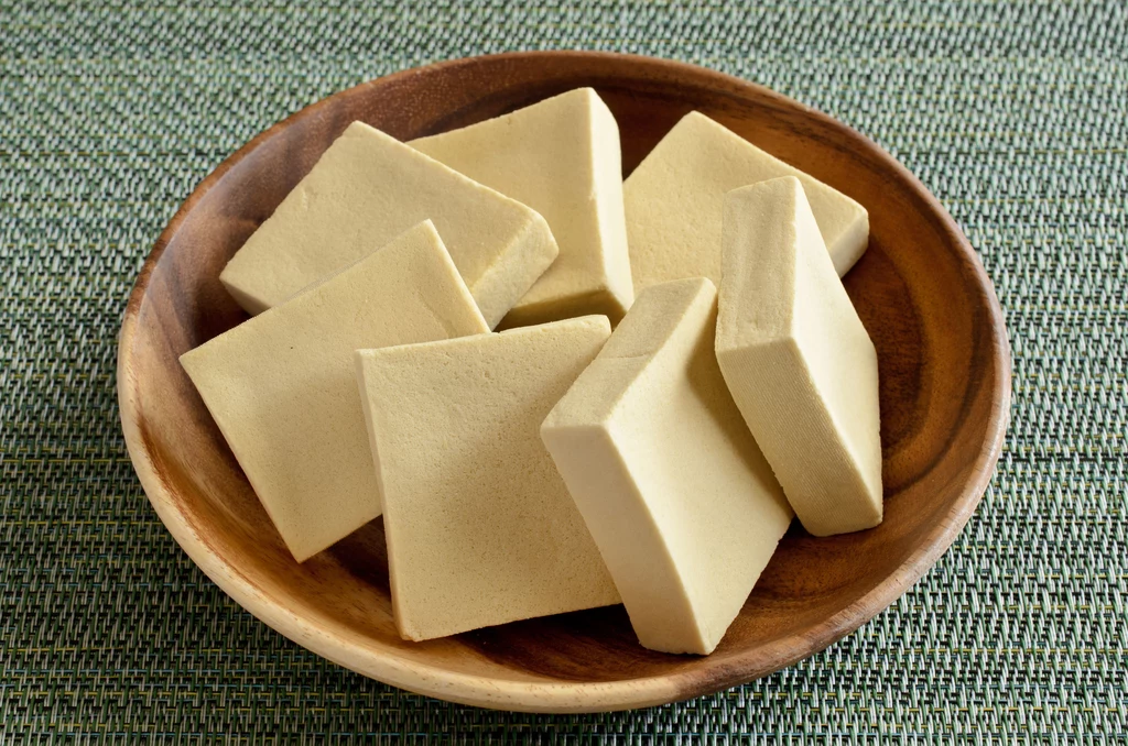 Tofu to sprasowany twaróg z mleka sojowego, które poddane zostaje procesowi koagulacji, w wyniku czego powstaje serwatka. Po odsączeniu pływającej w niej białej masy, uzyskuje się tofu. Jak je jeść? Po odsączeniu z zalewy można je kroić w plastry lub kostki, zjadać na zimno, zapiekać, smażyć i grillować. Po zblendowaniu będzie dobrym zagęszczaczem do sosów i zup. Kupując tofu warto zwrócić uwagę na konsystencję. Produkt dobrej jakości ma stałą i gładką gęstość, nie zbija się w grudki i nie rozpada. Tofu niejedno ma imię. W powszechnej sprzedaży dostępnych jest co najmniej pięć jego wariantów, a wśród nich: - tofu naturalne – uniwersalne, czyste tofu, które sprawdzi się w daniach obiadowych i sałatkach; - silken tofu - tofu jedwabiste, jest delikatniejsze niż naturalne, łatwo się rozpada; - tofu wędzone – słona nutka i wędzony posmak to dobry dodatek do zup, zapiekanek, dań na bazie ryżu i kasz; - tofu marynowane sosem sojowym jest zdecydowanie bardziej wyraziste w smaku, często serwowane w sałatkach i zimnych przekąskach; - tofu ziołowe, najczęściej z dodatkiem chilli lub czosnku. Tofu to sprasowany twaróg z mleka sojowego, które poddane zostaje procesowi koagulacji, w wyniku czego powstaje serwatka. Po odsączeniu pływającej w niej białej masy, uzyskuje się tofu. Jak je jeść? Po odsączeniu z zalewy można je kroić w plastry lub kostki, zjadać na zimno, zapiekać, smażyć i grillować. Po zblendowaniu będzie dobrym zagęszczaczem do sosów i zup. Kupując tofu warto zwrócić uwagę na konsystencję. Produkt dobrej jakości ma stałą i gładką gęstość, nie zbija się w grudki i nie rozpada. Tofu niejedno ma imię. W powszechnej sprzedaży dostępnych jest co najmniej pięć jego wariantów, a wśród nich: - tofu naturalne – uniwersalne, czyste tofu, które sprawdzi się w daniach obiadowych i sałatkach; - silken tofu - tofu jedwabiste, jest delikatniejsze niż naturalne, łatwo się rozpada; - tofu wędzone – słona nutka i wędzony posmak to dobry dodatek do zup, zapiekanek, dań na bazie ryżu i kasz; - tofu marynowane sosem sojowym jest zdecydowanie bardziej wyraziste w smaku, często serwowane w sałatkach i zimnych przekąskach; - tofu ziołowe, najczęściej z dodatkiem chilli lub czosnku.