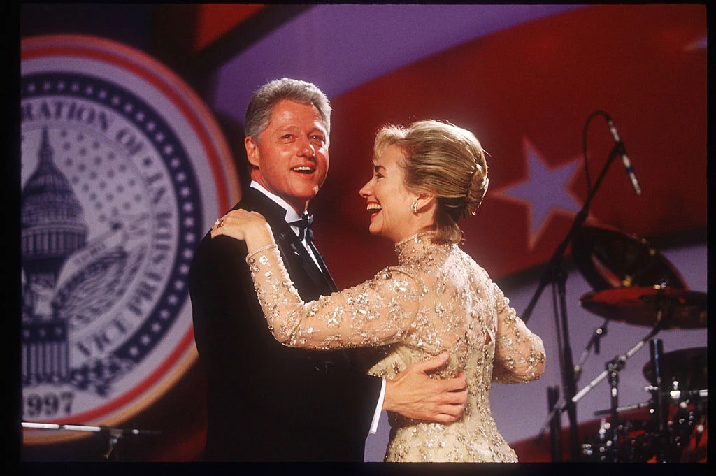 Hillary Clinton Zanim Hillary Clinton zaczęła ubierać się w garsonki, aby dopasować styl do funkcji sekretarza stanu, znacznie częściej widywano ją w sukienkach. Jako pierwsza dama miała ku temu wiele okazji. Jedną z nich był bal inauguracyjny jej męża, Billa Clintona, który wówczas rozpoczynał drugą kadencję prezydencką. Hillary pojawiła się na uroczystości w zachwycającej, kremowej sukni balowej projektu Oscara de la Renty. Kreacja została utkana ze złotej koronki, która pięknie mieniła się w blasku fleszy. Długi rękaw i wysoki dekolt dodał stylizacji elegancji. Hillary Clinton Zanim Hillary Clinton zaczęła ubierać się w garsonki, aby dopasować styl do funkcji sekretarza stanu, znacznie częściej widywano ją w sukienkach. Jako pierwsza dama miała ku temu wiele okazji. Jedną z nich był bal inauguracyjny jej męża, Billa Clintona, który wówczas rozpoczynał drugą kadencję prezydencką. Hillary pojawiła się na uroczystości w zachwycającej, kremowej sukni balowej projektu Oscara de la Renty. Kreacja została utkana ze złotej koronki, która pięknie mieniła się w blasku fleszy. Długi rękaw i wysoki dekolt dodał stylizacji elegancji.