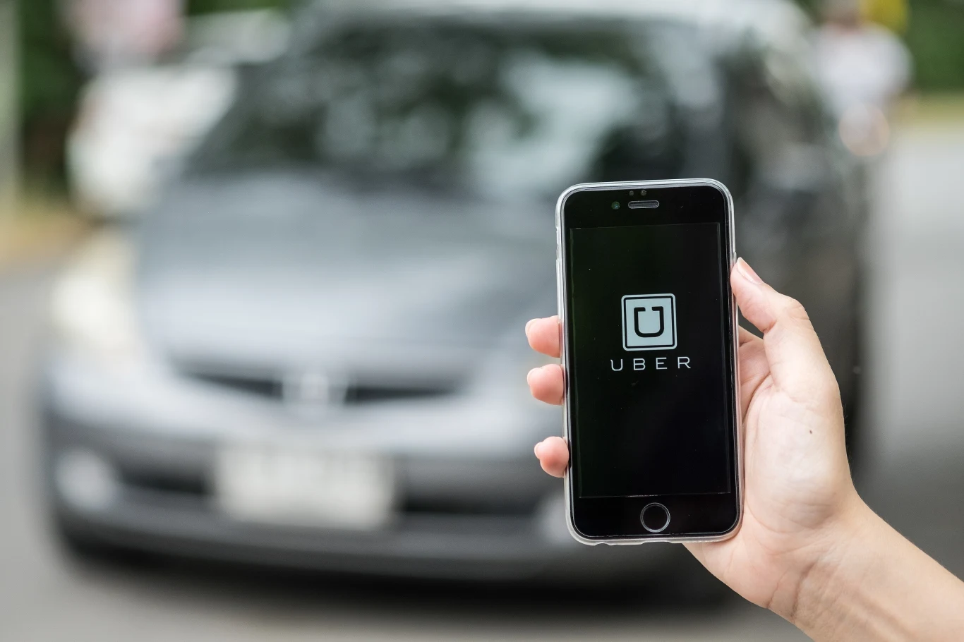MRPiPS zakończyło prace nad dyrektywą platformową. Czas na jej implementację mija w grudniu Dłoń trzymająca smartfona. Na czarnym ekranie słowo "Uber" i logo firmy. Tłem samochód osobowy.