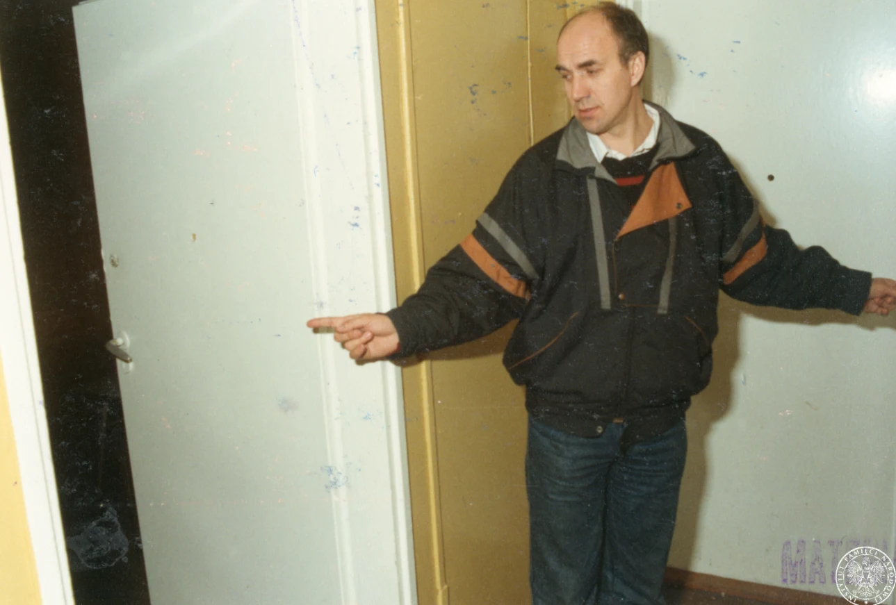 Stojący na korytarzu Antoni Mężydło wskazuje pomieszczenie, do którego był przyprowadzany w czasie porwania, 1991/03/19 . Dokumentacja eksperymentów śledczych do sprawy tzw. "toruńskich uprowadzeń" w lutym-marcu 1984 r