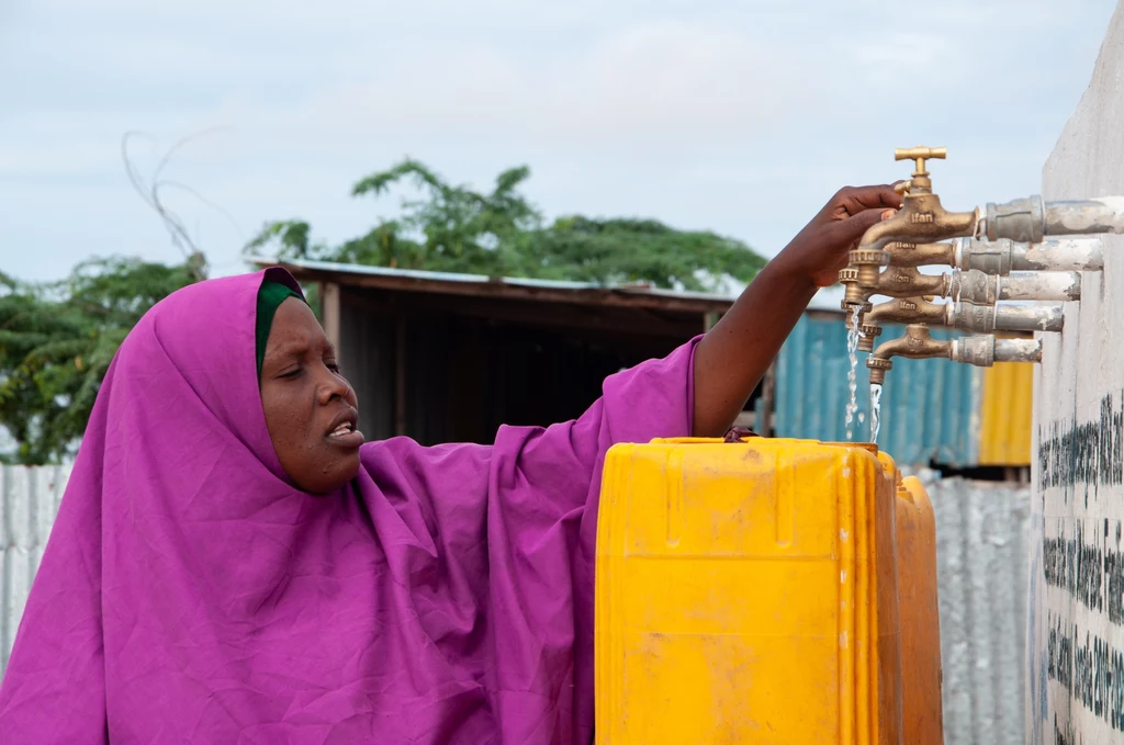 Kobieta napełniająca pojemnik na wodę, Somalia. fot. PAH
