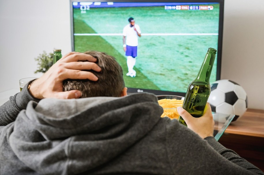 Mecz drużyny piłkarskiej w TV. Mężczyzna oglądający mecz w telewizji.