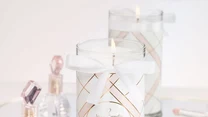 Świeca Beauty marki JewelCandle zachwyca aromatem jabłek, czarnego bzu, i frezji z wonią róży i fiołka. Świeca, która jest ręcznie malowana, skrywa w sobie srebrną biżuterię platerowaną różowym złotem.