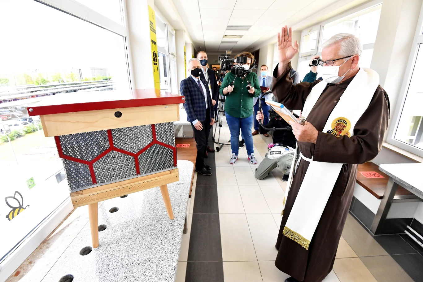 Ojciec Józef Mońko święci ule podczas otwarcia pierwszej pasieki z recyklingu,