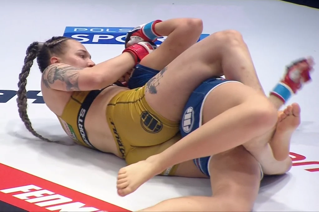 Paulina Paola (w żółtym stroju) duszeniem zza pleców zmusiła rywalkę do odklepania Paulina Paola (w żółtym stroju) duszeniem zza pleców zmusiła rywalkę do odklepania