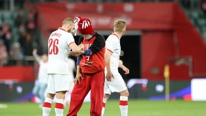 Tymoteusz Puchacz składa podpis na ręce kibica, który wbiegł na murawę