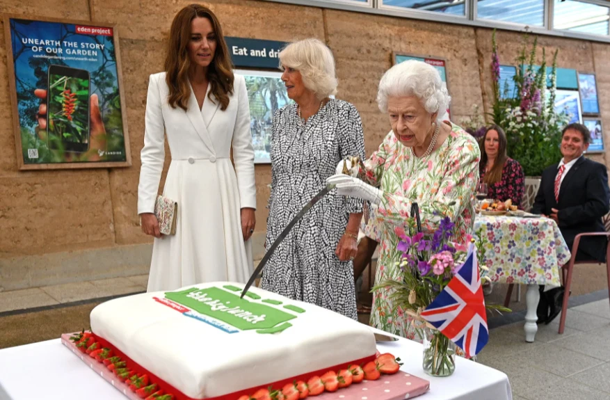 Królowa Elżbieta kroi tort ceremonialną szpadą Królowa Elżbieta kroi tort ceremonialną szpadą