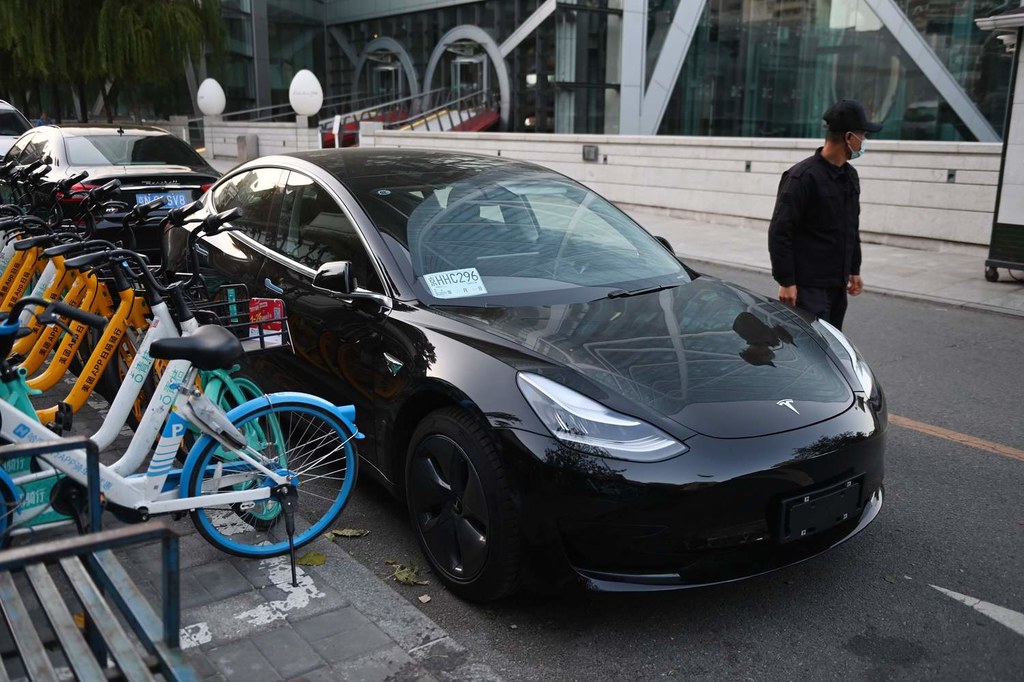 Tesla Model 3 na tle salonu Tesli w Pekinie w Chinach.