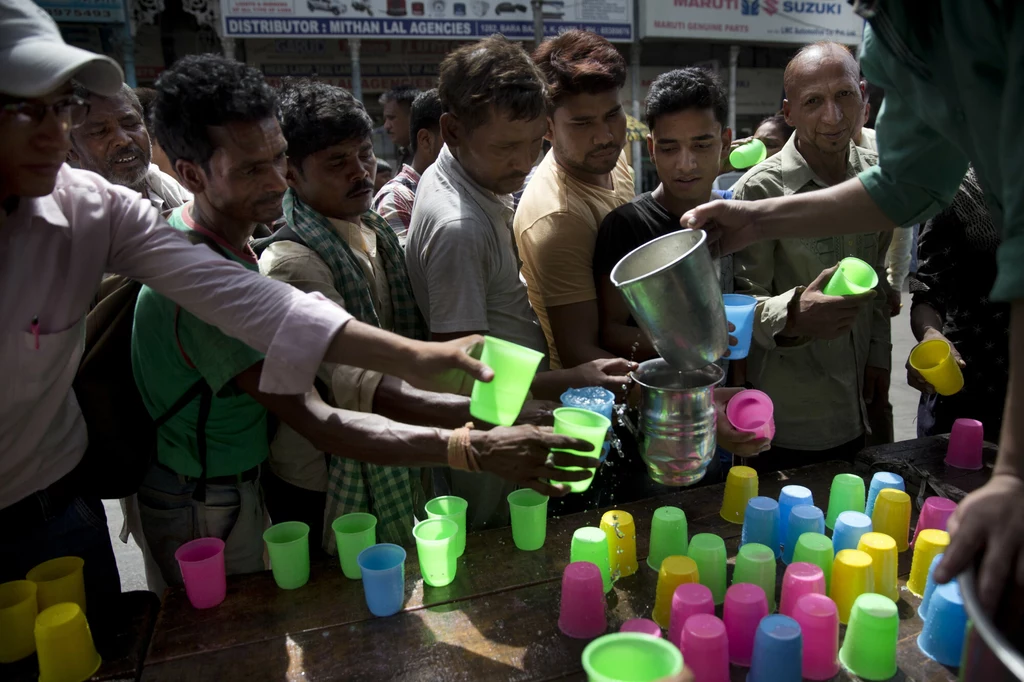 Hindusi w Delhi przyjmujący darmowy zimny napój w upalny dzień. 