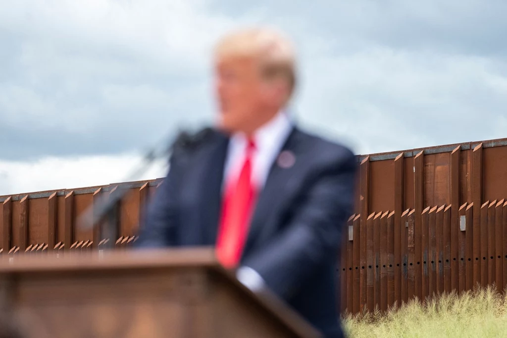Donald Trump na tle muru na granicy z Meksykiem.