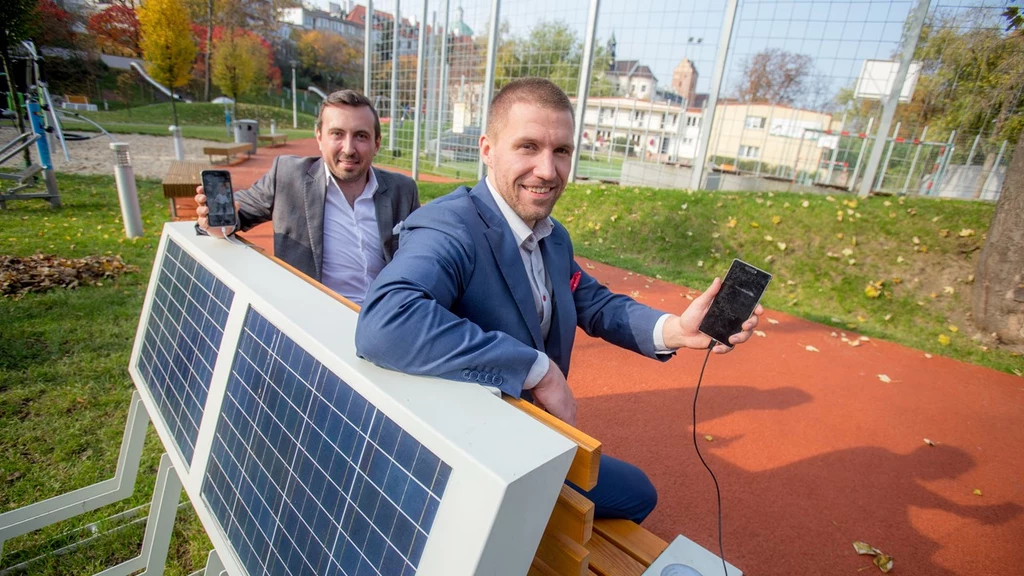 CEO startupu SEEDiA Piotr Hołubowicz (po prawej) i współzałożyciel firmy Artur Racicki, siedzący na solarnej ławce wyprodukowanej przez SEEDiA.