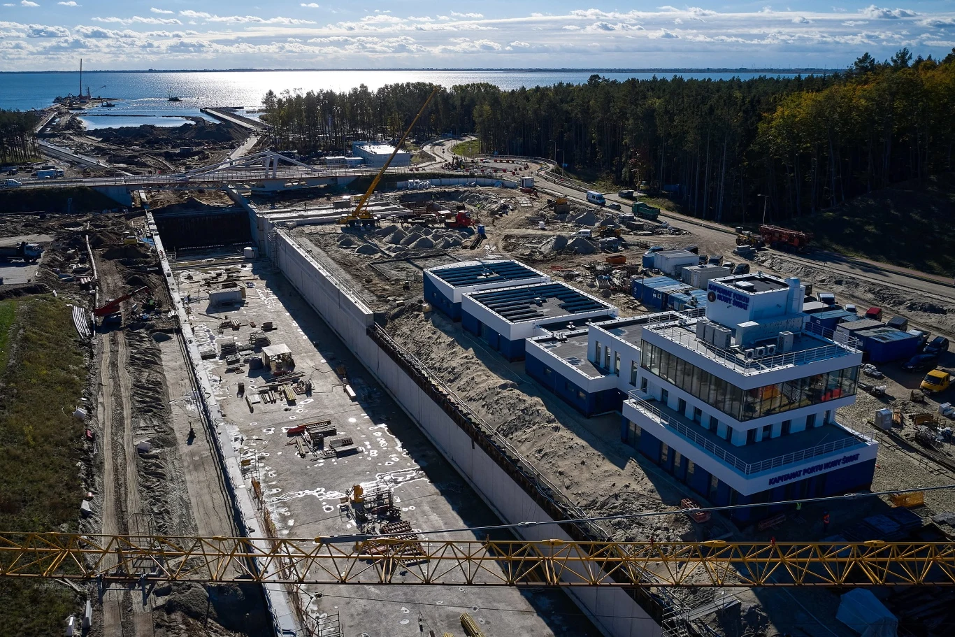 Cały czas odbywa się również dostawa i montaż prefabrykatów muru oporowego. Wykonywane jest podłoże i warstwa wyrównawcza z betonu. Nie mniej dzieje się w rejonie budowanego kanału żeglugowego oraz śluzy. Dzięki nim, jednostki pływające będą mogły się dostać od strony Morza Bałtyckiego do Zalewu Wiślanego i na odwrót.