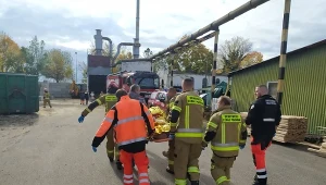 Strażacy i ratownicy medyczni niosą kobietę do śmigłowca