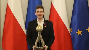 Jan-Krzysztof Duda z szachowym Pucharem Świata w rękach oraz ze złotym Krzyżem Zasługi na piersi