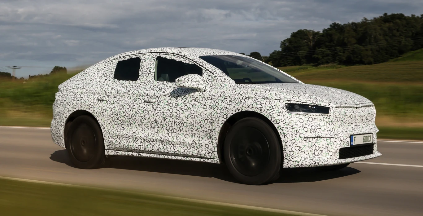 Skoda Enyaq iV Coupe to dynamiczniej wystylizowana odmiana dobrze nam już znanego modelu. Producent stara się podkreślić jego wyjątkowość i podgrzać atmosferę przed premierą, prezentując całkowicie zamaskowane egzemplarze, ale nas to nie zwiedzie. Widzieliśmy już na żywo Enyaka iV Coupe, testowanego na czeskich drogach i miał on oklejony tylko tył. Pozostała część nadwozia pozostanie więc niezmieniona.