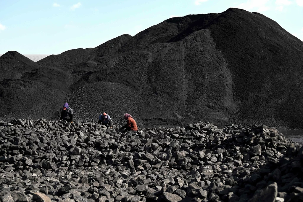 Pracownicy sortują węgiel w pobliżu kopalni tego surowca w Datong w Chinach.
