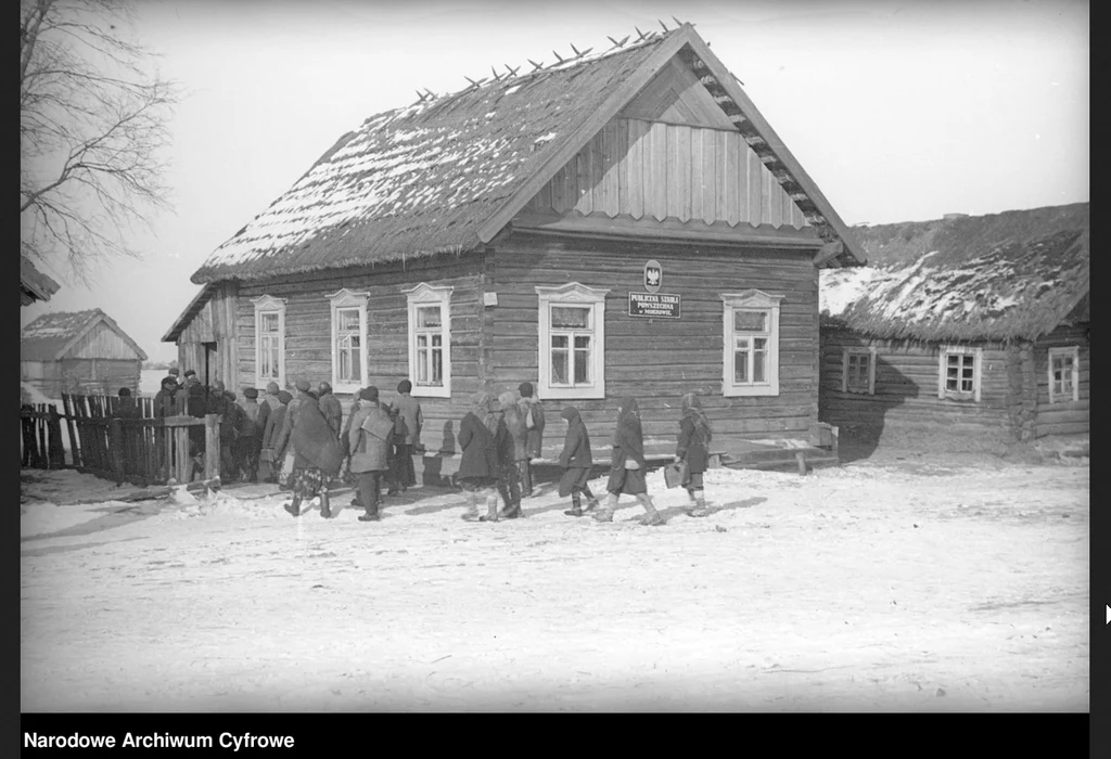 Drewniany budynek Publicznej Szkoły Powszechnej w Mokrowie. Dzieci wchodzące do budynku, lata 1928-1931 Drewniany budynek Publicznej Szkoły Powszechnej w Mokrowie. Dzieci wchodzące do budynku, lata 1928-1931