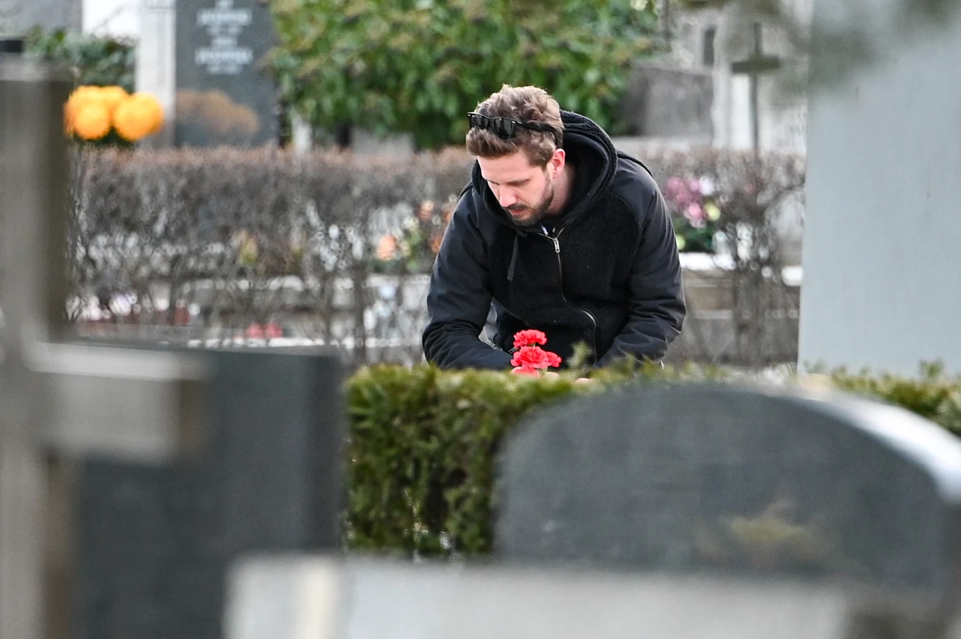 Antek dekoruje grób kupionymi przez siebie czerwonymi goździkami