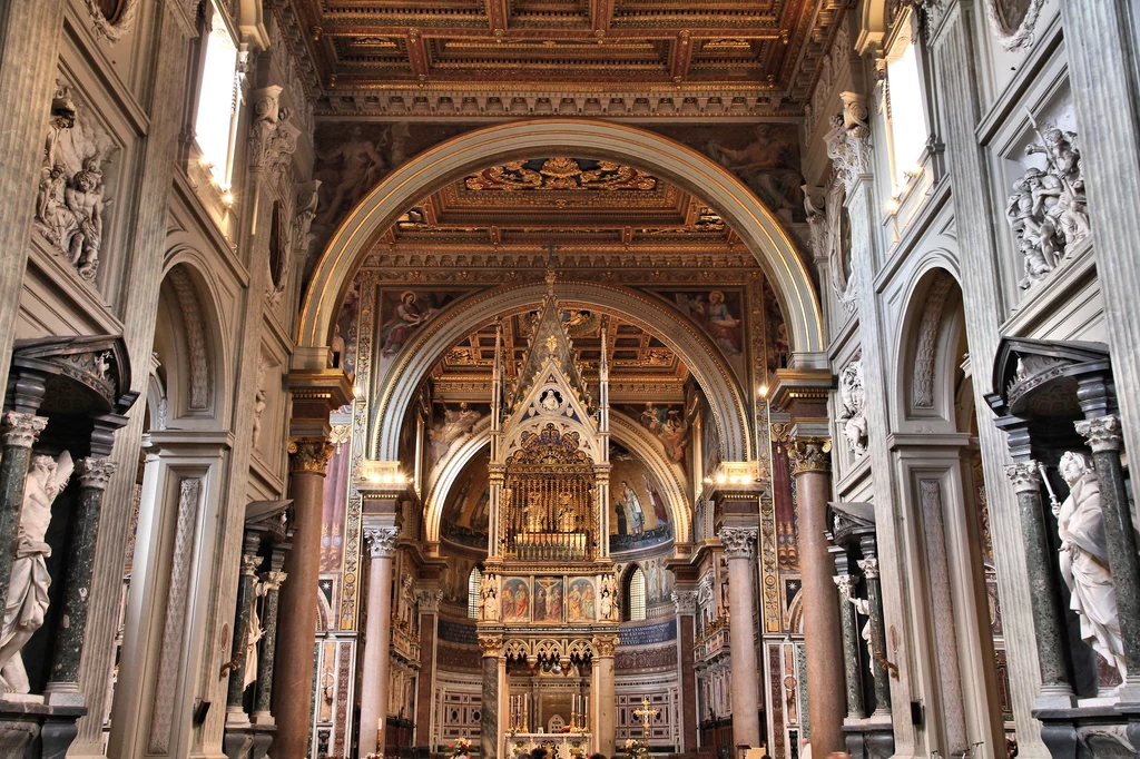 Za ołtarzem głównym, pod baldachimem, znajduje się prezbiterium a przy jego końcu stoi tron papieski z białego marmuru