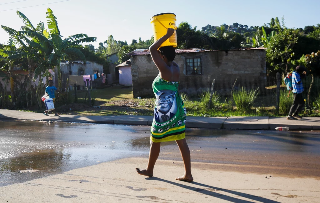 Kobieta niesie wiadro wody, po tym jak powodzie uszkodziły infrastrukturę wodną w RPA.
