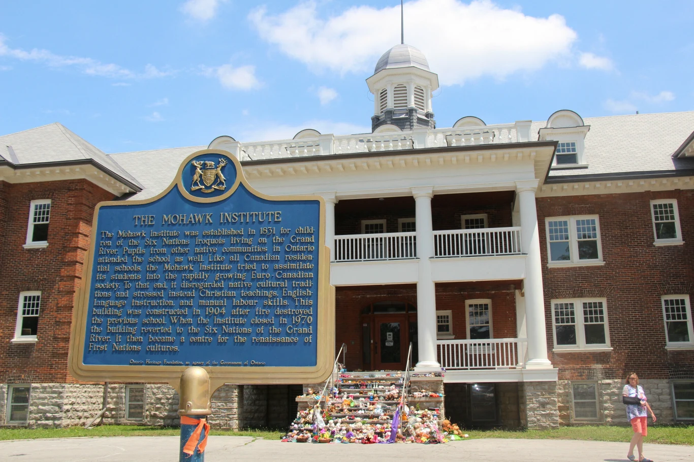 Kwiaty, buty i zabawki przed wejściem do dawnej szkoły dla rdzennych dzieci Kwiaty, buty i zabawki przed wejściem do dawnej szkoły dla rdzennych dzieci