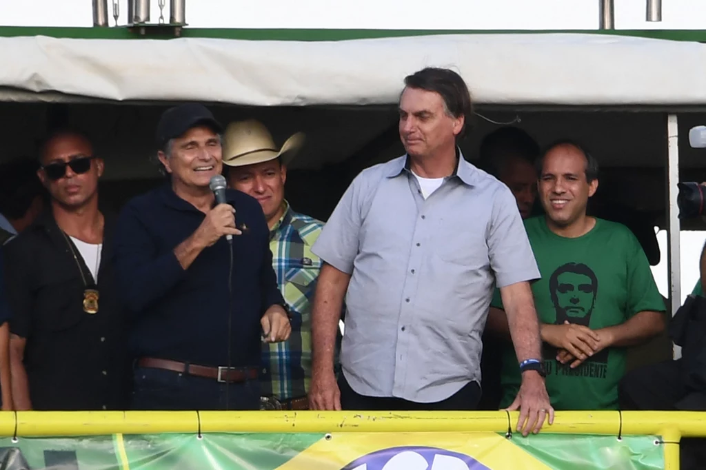 Nelson Piquet (przy mikrofonie) oraz Jair Bolsonaro (w jasnej koszuli) na demonstracji rolników w Brazylii w roku 2021. Nelson Piquet (przy mikrofonie) oraz Jair Bolsonaro (w jasnej koszuli) na demonstracji rolników w Brazylii w roku 2021.