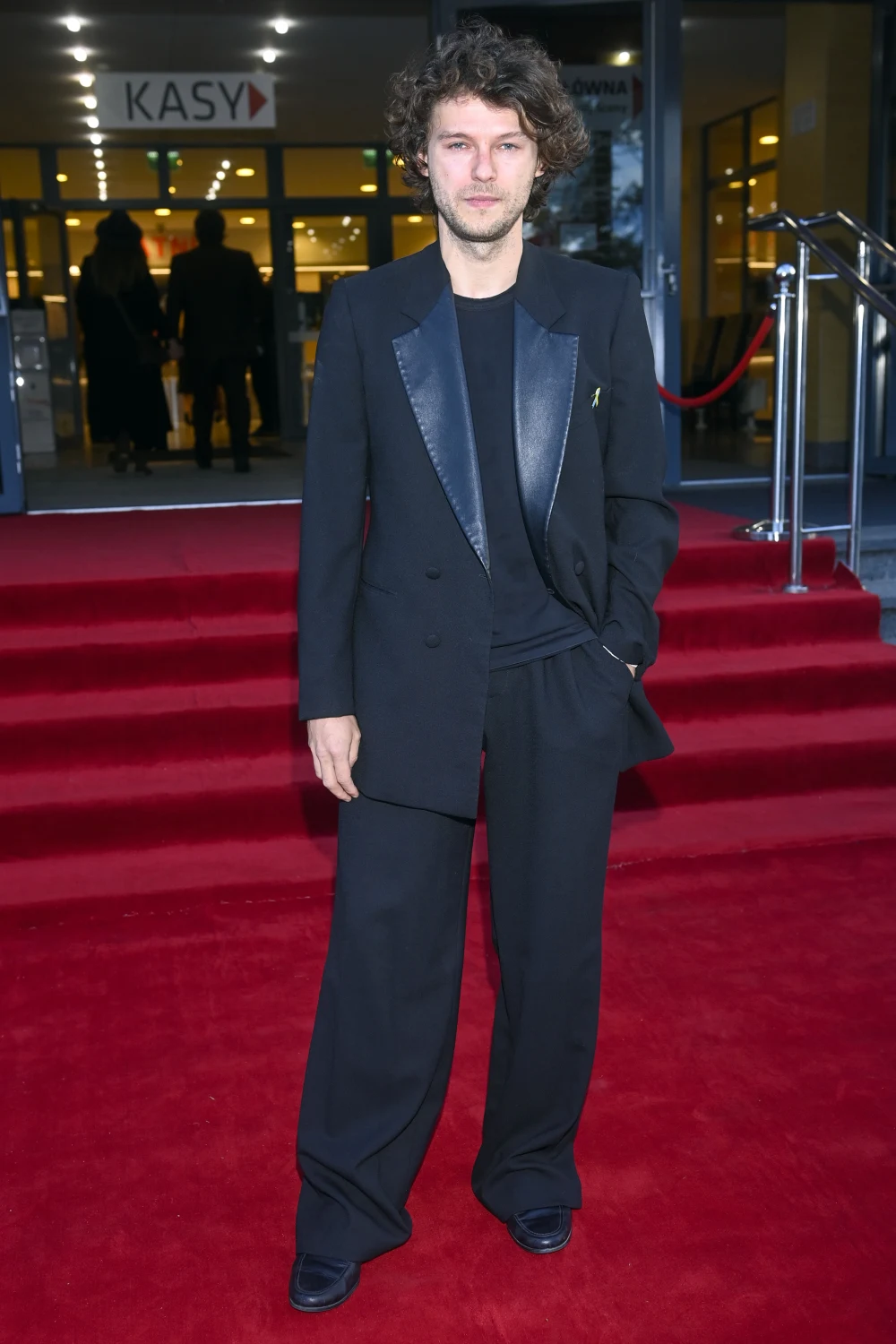 Mateusz Kościukiewicz na czerwonym dywanie przed Teatrem Muzycznym.