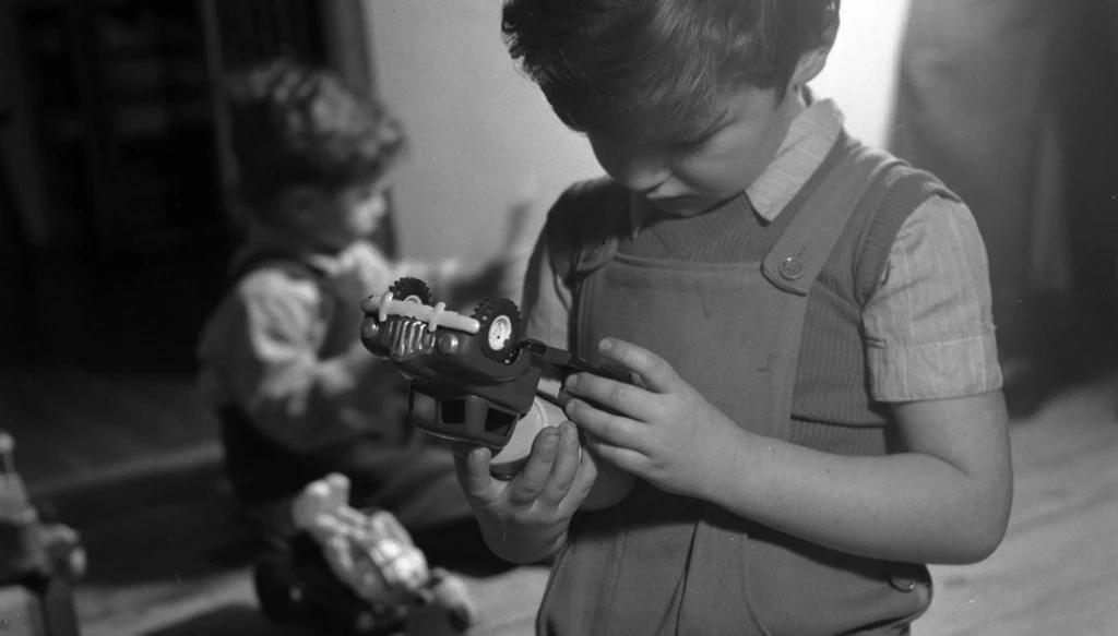 Chłopiec bawiący się samochodem-ciężarkówką w latach 50.