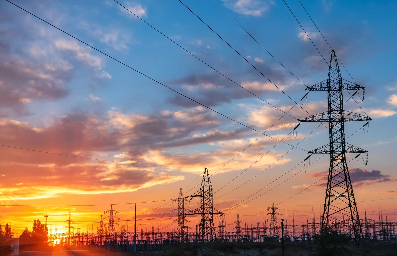 Znowu wyłączono tysiące instalacji OZE. Rząd szykuje rozwiązania Linie wysokiego napięcia i stalowe słupy na tle zachodu słońca, ilustracja Polskich Sieci Elektroenergetycznych.