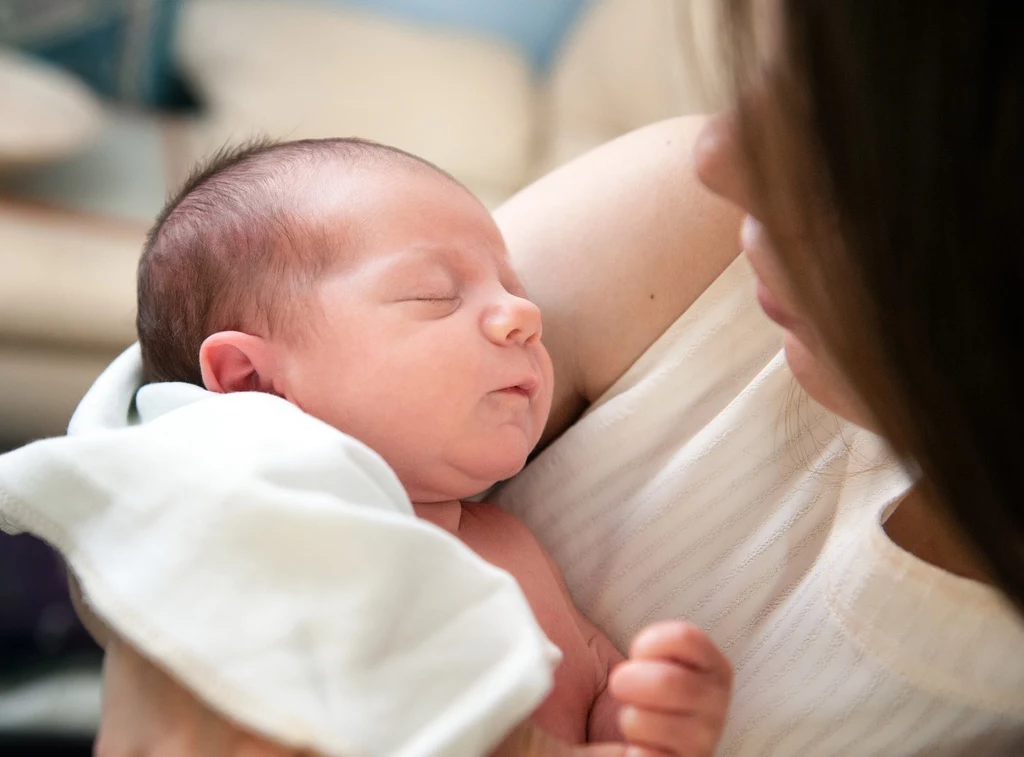 Mama przytula noworodka po karmieniu piersią