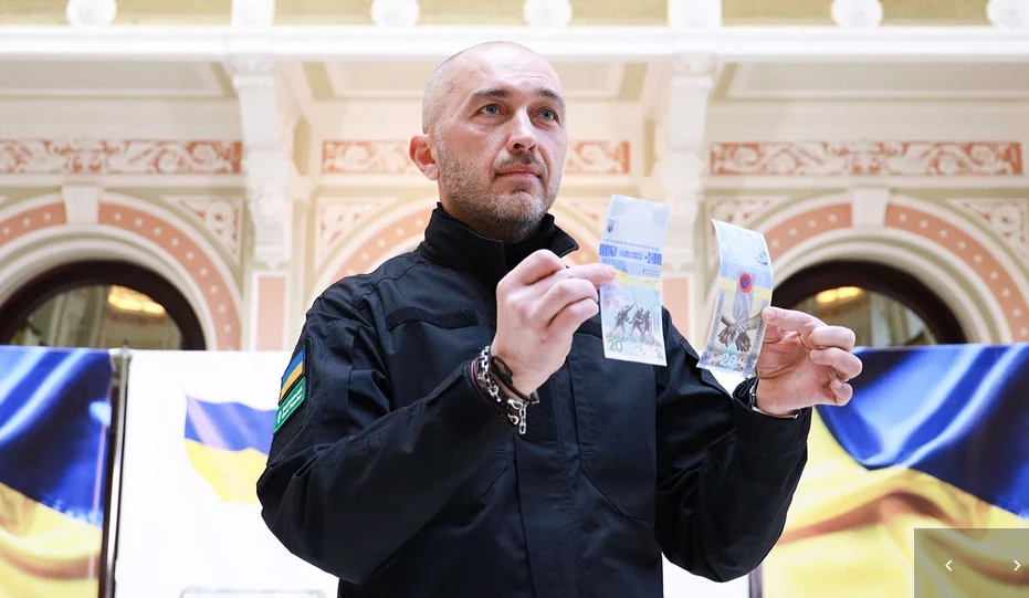 "Nie mogliśmy nie odnotować tej daty - rocznicy inwazji na pełną skalę; tego dramatycznego, szokującego, rozstrzelanego roku naszego życia" - powiedział na prezentacji szef NBU Andrij Pyszny. Nowy banknot o nominale 20 hrywien (ok. 2,4 PLN) jest oficjalnym środkiem płatniczym. Zarazem - jak mówił szef banku centralnego - stanowi "przypomnienie o wojnie o niepodległość i suwerenność Ukrainy". Fot. NBU "Nie mogliśmy nie odnotować tej daty - rocznicy inwazji na pełną skalę; tego dramatycznego, szokującego, rozstrzelanego roku naszego życia" - powiedział na prezentacji szef NBU Andrij Pyszny. Nowy banknot o nominale 20 hrywien (ok. 2,4 PLN) jest oficjalnym środkiem płatniczym. Zarazem - jak mówił szef banku centralnego - stanowi "przypomnienie o wojnie o niepodległość i suwerenność Ukrainy". Fot. NBU