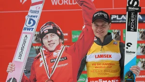 Anze Lanisek z tekturową postacią Dawida Kubackiego na podium klasyfikacji generalnej PŚ w skokach narciarskich