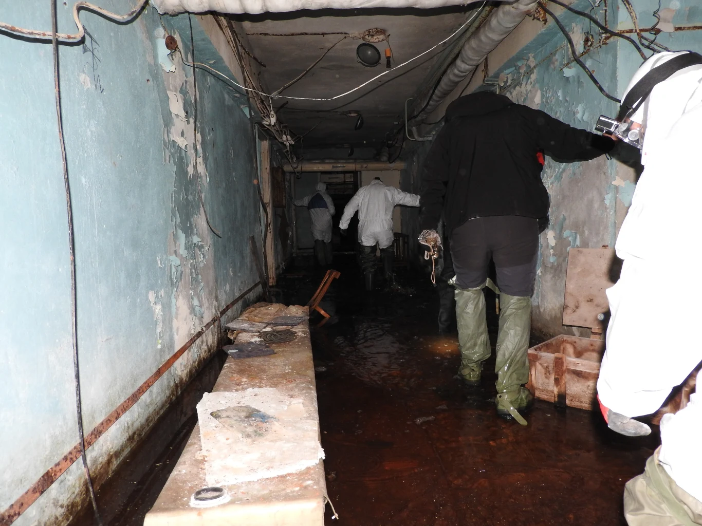 Eksploracja Prypeci w 2018 roku. Na zdjęciu turyści w zalanych wodą podziemiach miejskiej fabryki "Jupiter". Część osób w obawie przed radioaktywnym pyłem zakłada skafandry i kombinezony, tak by chronić odsłonięte części ciała Eksploracja Prypeci w 2018 roku. Na zdjęciu turyści w zalanych wodą podziemiach miejskiej fabryki "Jupiter". Część osób w obawie przed radioaktywnym pyłem zakłada skafandry i kombinezony, tak by chronić odsłonięte części ciała