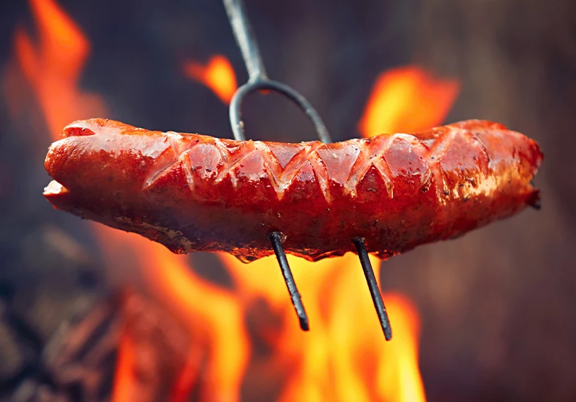 Upieczona kiełbasa nadziana na kij do ogniska 