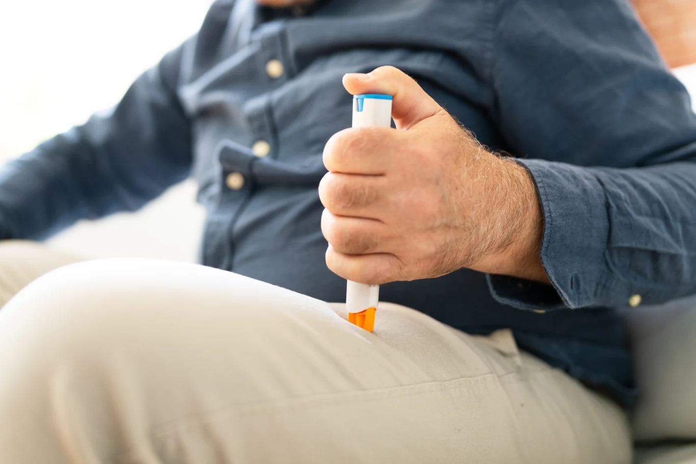 Leki GLP-1: bilans korzyści i zgłoszeń działań niepożądanych wg danych MHRA Mężczyzna wbijający w udo ampułko-strzykawkę
