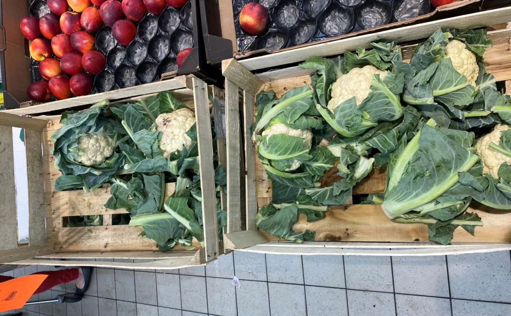 Dwie skrzynki z kalafiorami wystawionymi na szczycie działu warzywnego. Mimo, że warzywo tego dnia było w promocji, od rana pojawiały się oberwane liście.